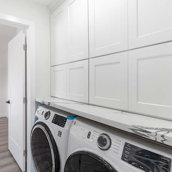 a laundry room with white cabinets and a white washer and dryer at seaview terrace apartment homes, california