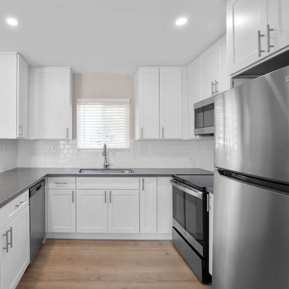 a modern kitchen with white cabinets and a stainless steel refrigerator.