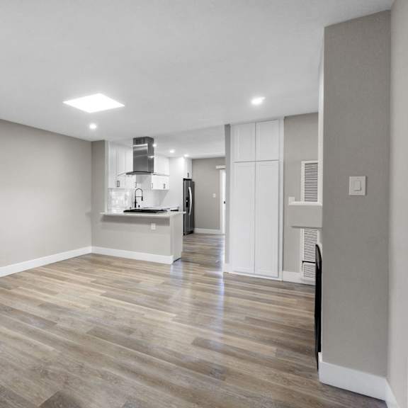 an empty room with a hard wood floor and white walls at ocean breeze terrace apartment, huntington beach, california