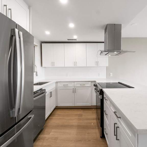 a modern kitchen with a stainless steel refrigerator and white cabinets.at ocean edge @ laguna beach, laguna beach california