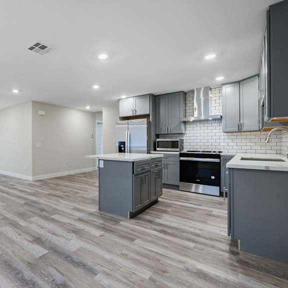 an empty kitchen and living room with a white and gray kitchen