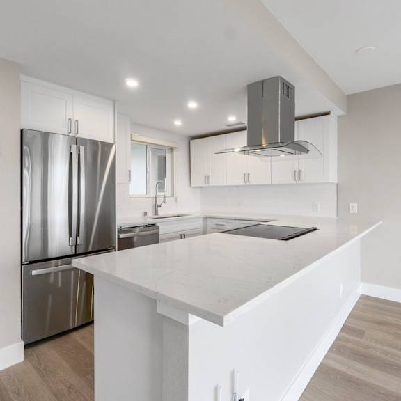 a modern kitchen with a white island and stainless steel appliances.at ocean edge @ laguna beach, laguna beach, ca