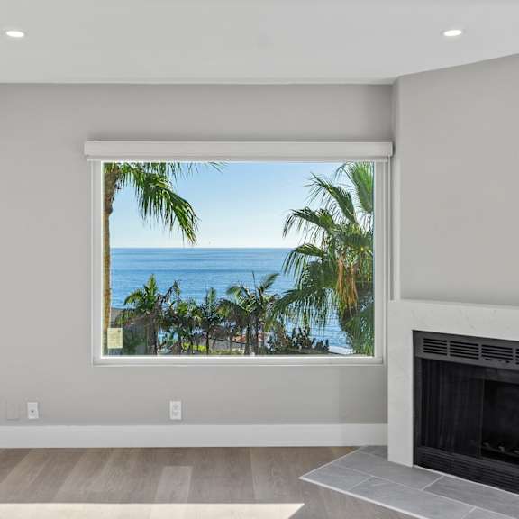 a modern living room with a fireplace and a view of the ocean through a large window.at ocean edge @ laguna beach, california