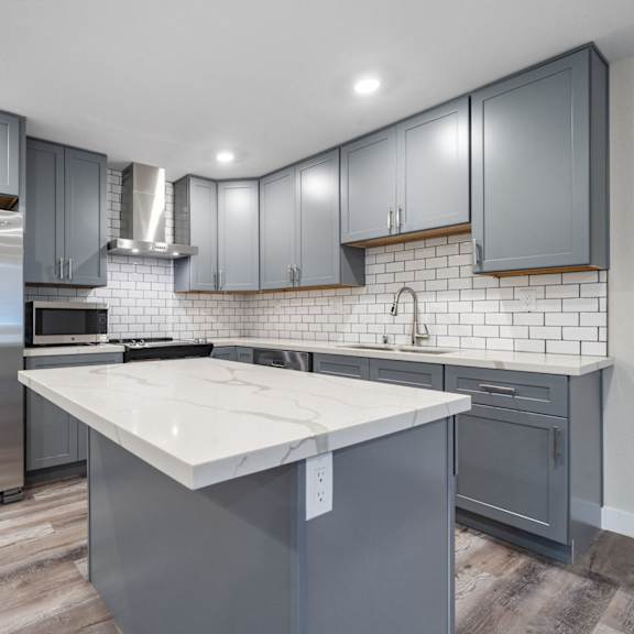 a modern kitchen with stainless steel appliances and white counter tops