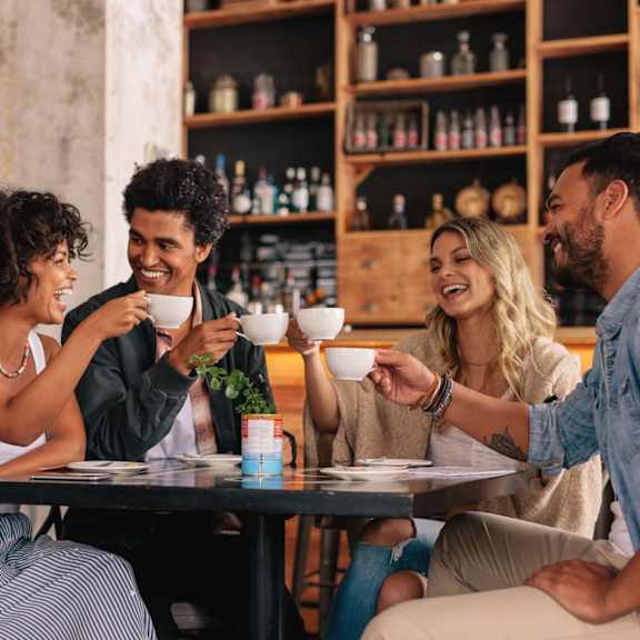 friends enjoying coffee in community cafe at nineteen90 apartment homes, costa mesa