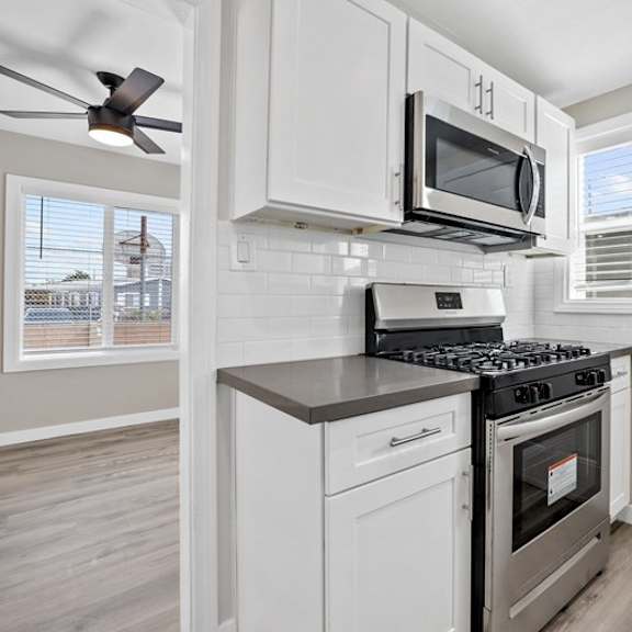 a kitchen with a stove and a microwave at huntington manor homes apartment, huntington beach