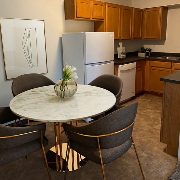 a kitchen with a white refrigerator freezer next to a table with four chairs