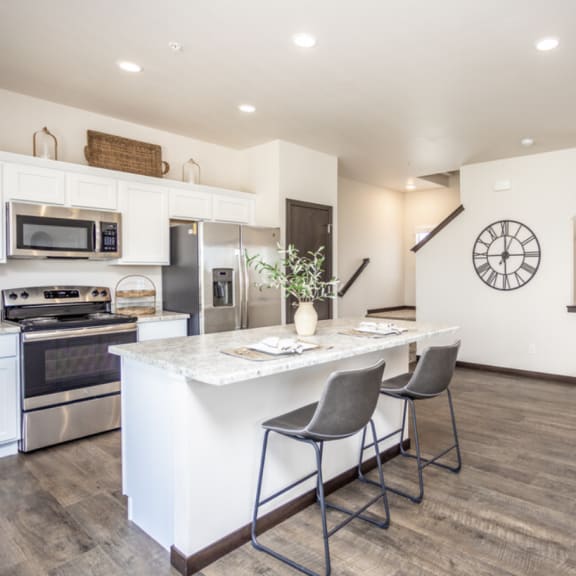 a kitchen with white cabinets and a marble counter top