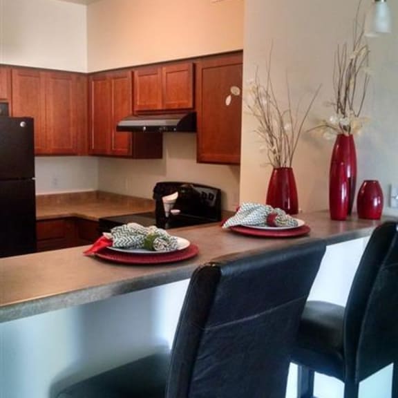 a kitchen with a counter and three chairs