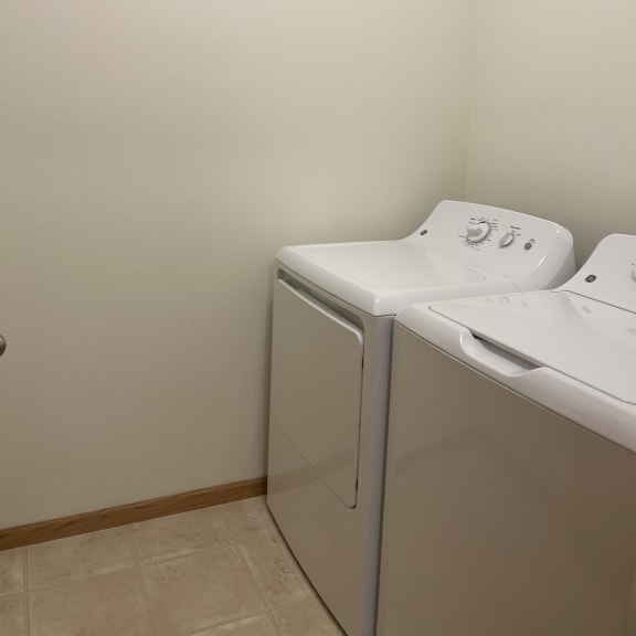 a washer and dryer in a laundry room with a white wall and tile