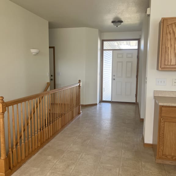a view from the top of a staircase into a hallway with a door and a