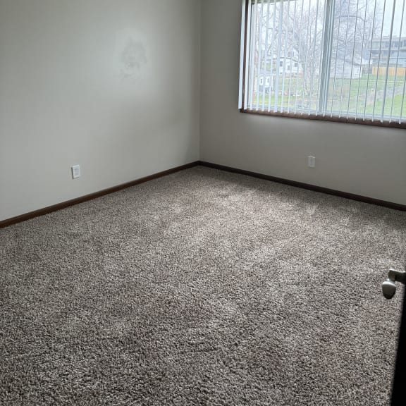 an empty room with a ceiling fan and a window