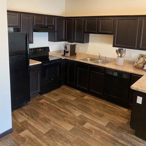 a kitchen with dark cabinets and a wooden floor