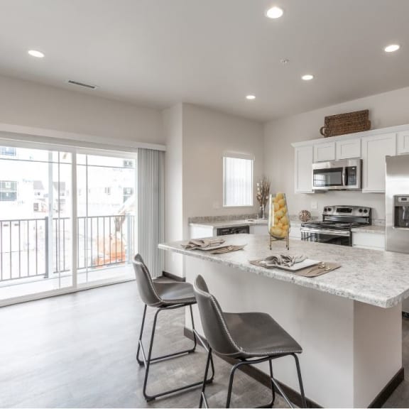 a kitchen with a marble counter top and a stainless steel refrigerator