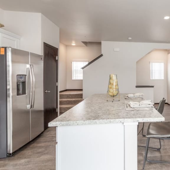 a kitchen with a marble counter top and a stainless steel refrigerator