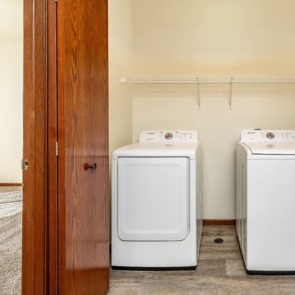 two washers and dryers in a laundry room with a wooden door