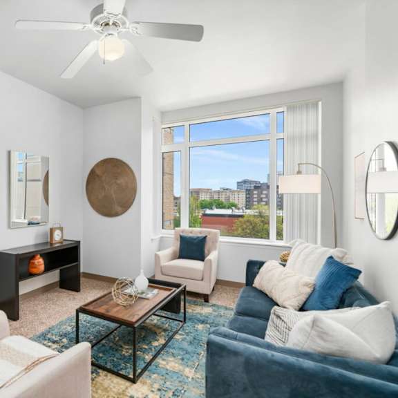 a living room with a white ceiling fan and a large window. at pacific tower apartments, portland, or