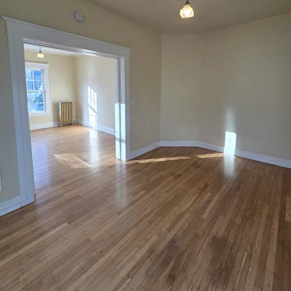 a wooden floor leads up to a window in a room with a white ceiling. at casa del rey apartments, oregon