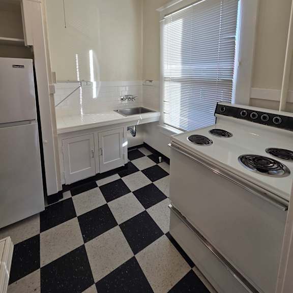 a kitchen with a checkered floor and a stove top oven. at casa del rey apartments, portland