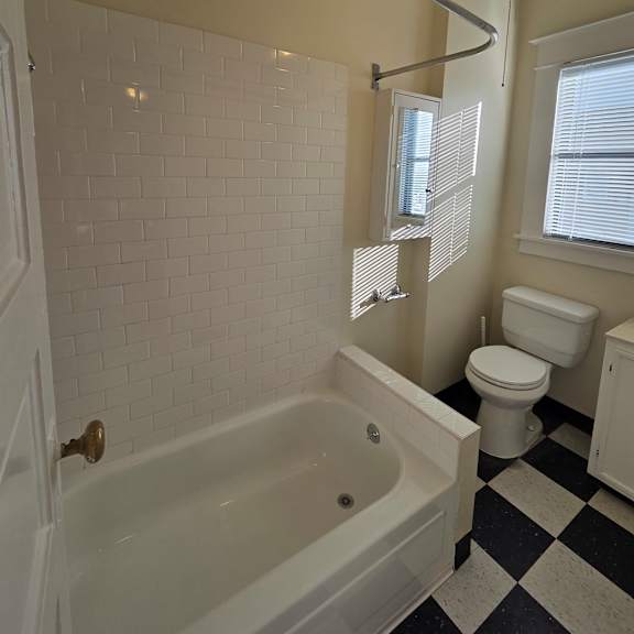 a bathroom with a skylight and a black and white checkered floor. at casa del rey apartments, portland, oregon