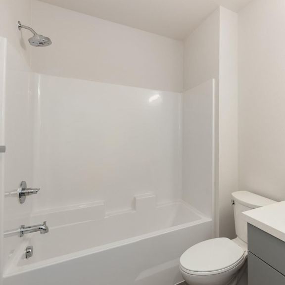 a white bathroom with a toilet, sink, and bathtub.