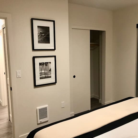 a bedroom with a bed, two pictures on the wall, and a door.