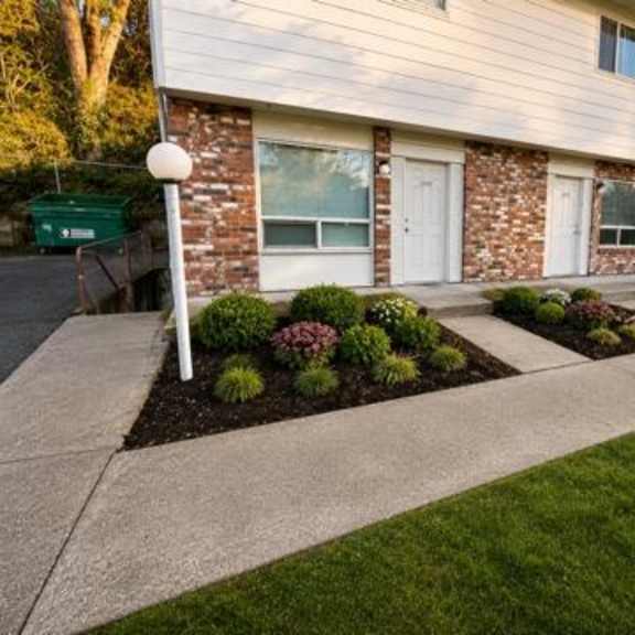 a house with a white door and windows, and a small garden in front.