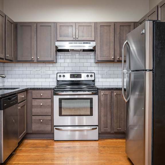 a modern kitchen with a stainless steel refrigerator, stainless steel appliances, and wooden cabinets.