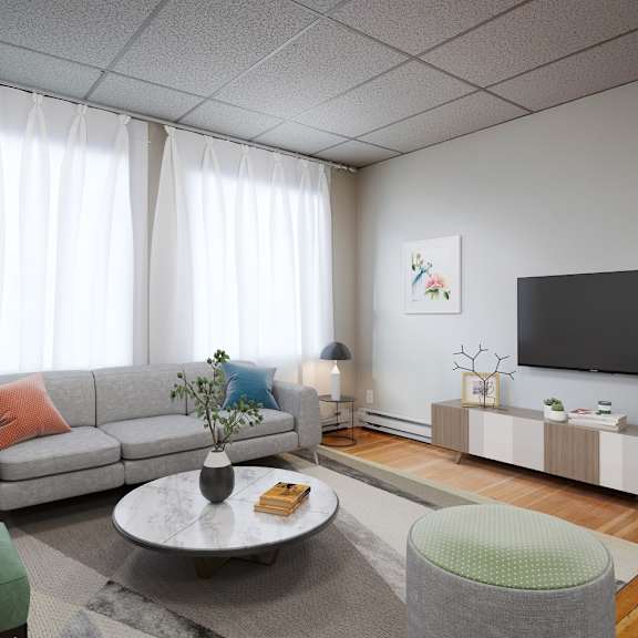 a living room with a grey sofa, a green armchair, a grey coffee table, a grey side table, a white wall, a black tv, a white curtain, and a grey floor.
