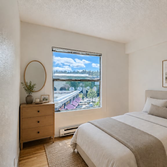 a bedroom with a large bed, a window with a view, and a wooden dresser.