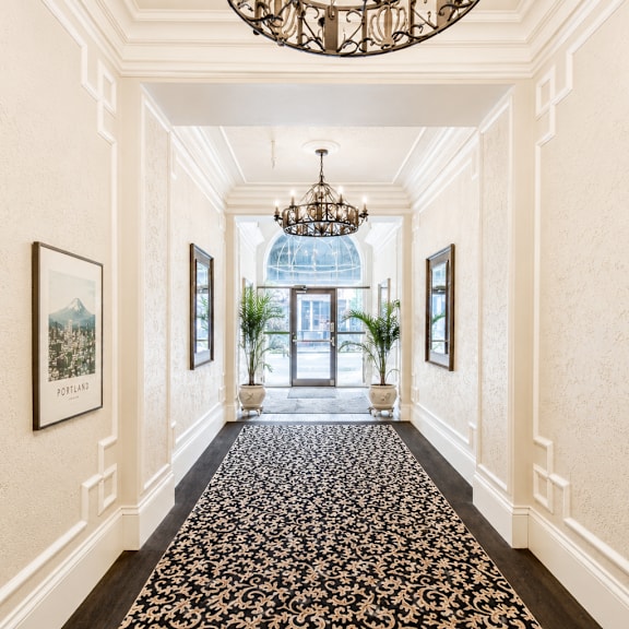 a hallway with a chandelier, framed pictures, and a floral carpet.
