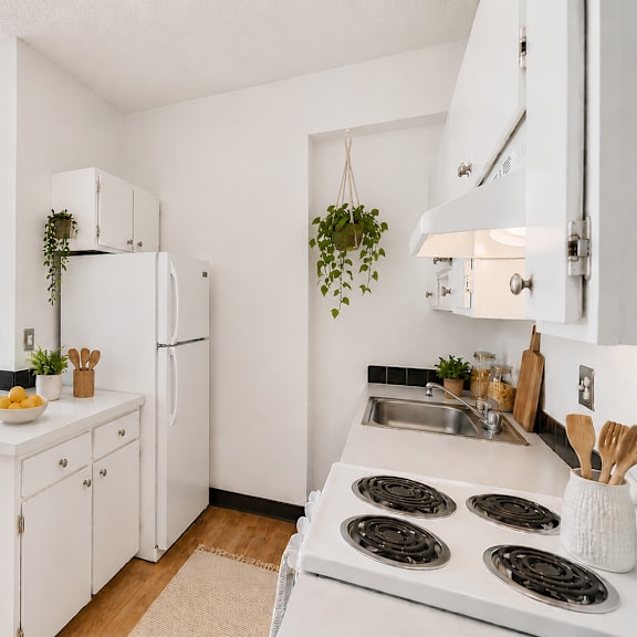 a white kitchen with a stove top oven and a fridge.