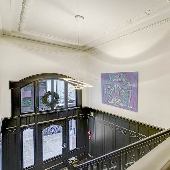 a staircase with a green railing and a purple painting on the wall at clay & tiffany, portland, 97201