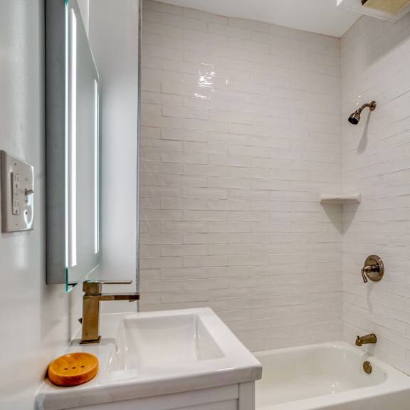 a white bathroom with a sink, mirror, and bathtub at clay & tiffany, portland, 97201