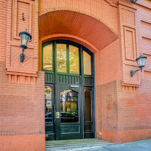 a red brick building with a black door and two lamps on either side at clay & tiffany, portland, 97201