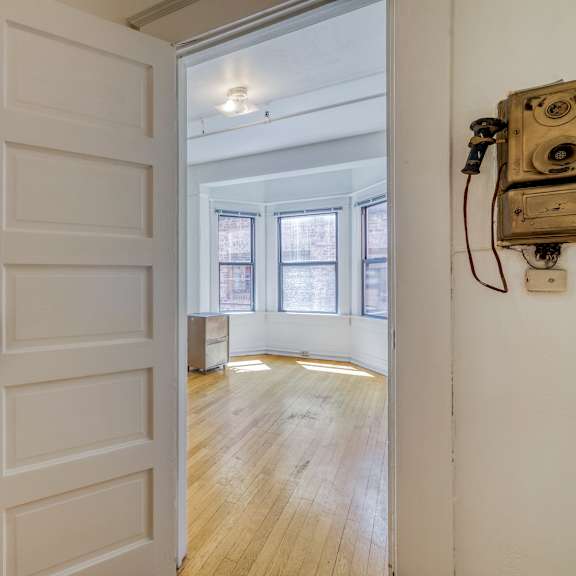 a white door with a brass handle is open to a room with wooden floors and a window at clay & tiffany, portland, 97201