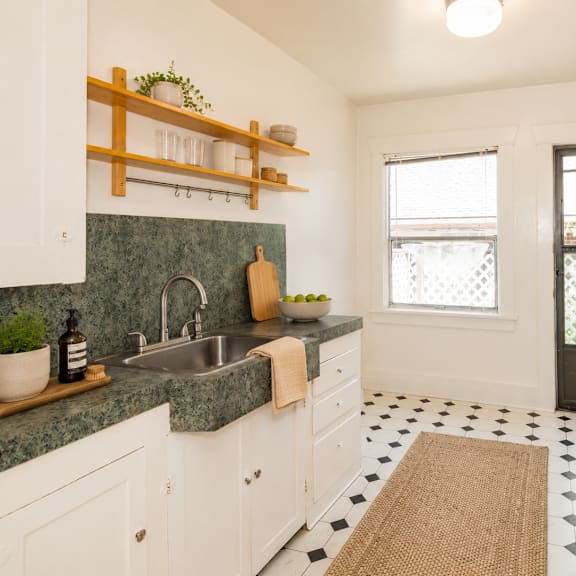 a kitchen with white cabinets and a green counter top.