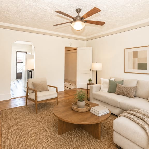 a living room with a white couch, a wooden coffee table, and a ceiling fan.