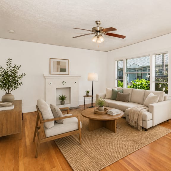 a living room with a fireplace, a sofa, a chair, a coffee table, and a potted plant.