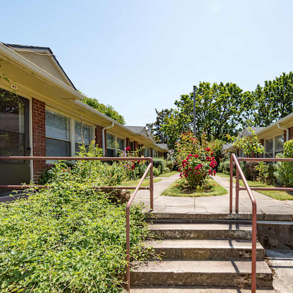a row of houses with a red metal railing in front of them.