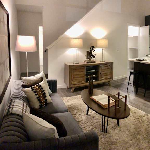 a modern living room with a kitchen area in the background.