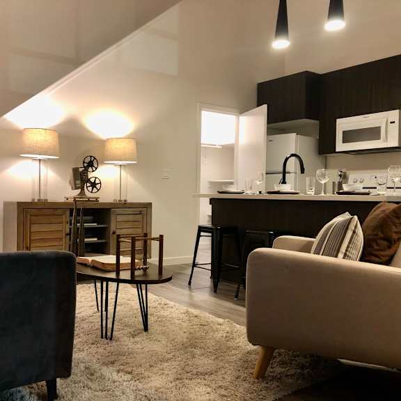 a living room with a couch, chair, and a kitchen area in the background.