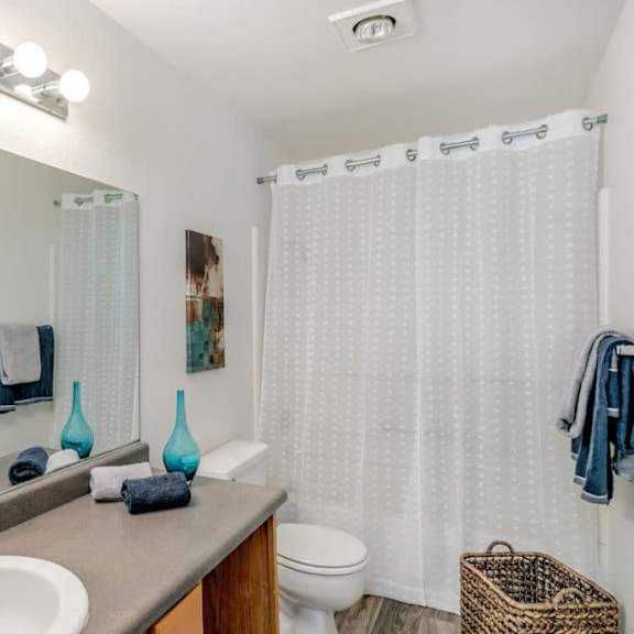 a bathroom with a white shower curtain and a white toilet.at alder creek apartments, washington