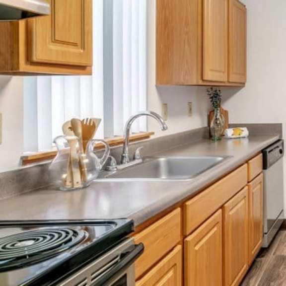 a kitchen with wooden cabinets and a black refrigerator.at alder creek apartments, vancouver washington