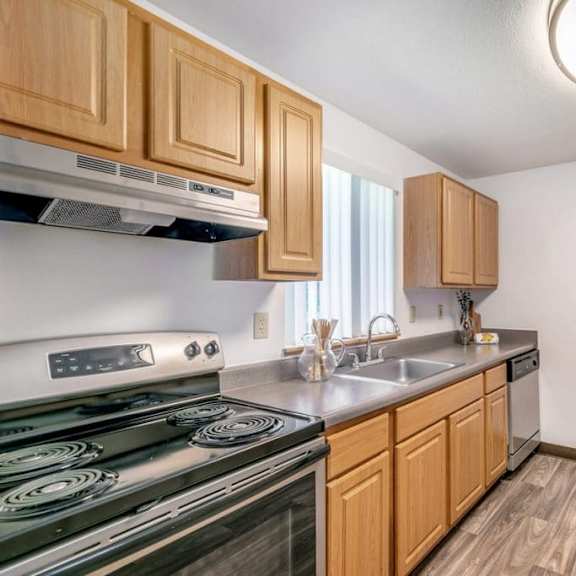 a kitchen with wooden cabinets and a black stove top oven.at alder creek apartments, vancouver, wa 98682