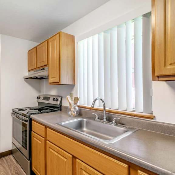 a kitchen with wooden cabinets and a stainless steel sink.at alder creek apartments, vancouver, wa