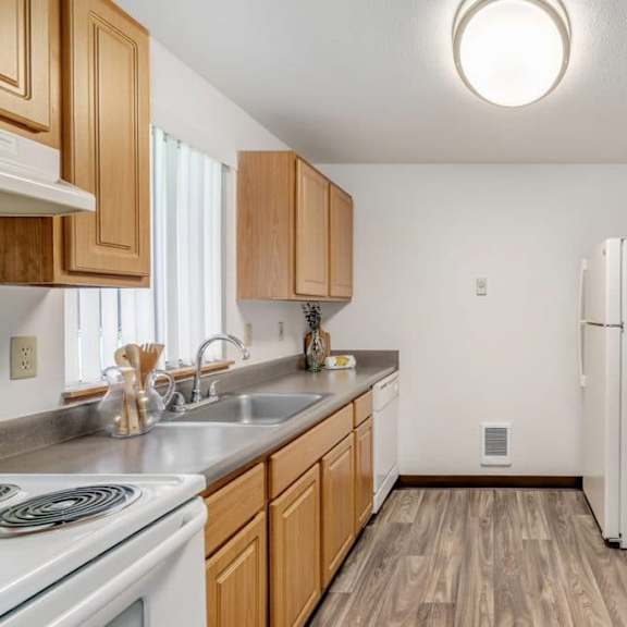 a kitchen with wooden cabinets and a white refrigerator.at alder creek apartments, vancouver, wa 98682