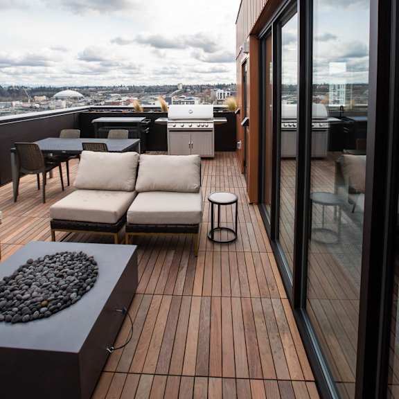 a deck on the roof of a building with furniture and a grill at analog tacoma, tacoma