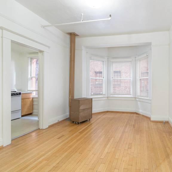 an empty living room with wood floors and a bay window at clay & tiffany, portland, or, 97201