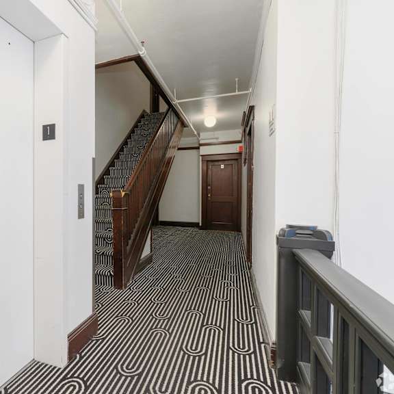 a hallway with stairs and a black and white geometric flooring at clay & tiffany, portland, or, 97201